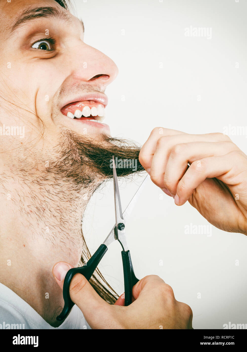 Cut and shave concept. Young man with long beard holding scissors. Boy