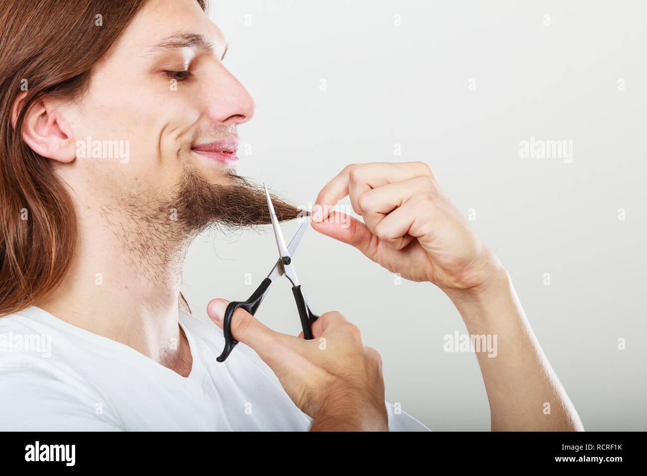 Cut and shave concept. Young man with long beard holding scissors. Boy