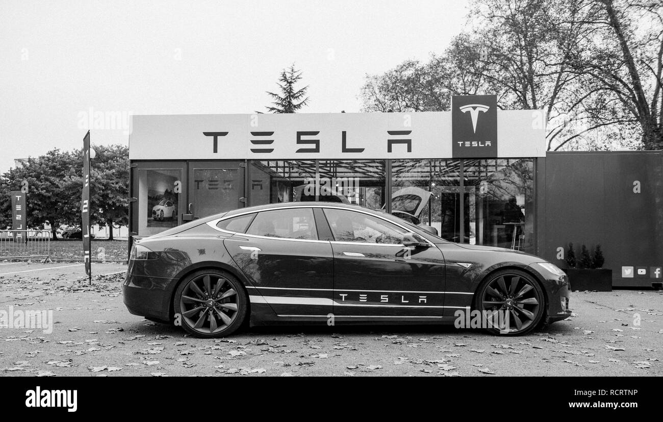 PARIS, FRANCE - NOV 29, 2014: New Tesla Model S showroom parked in front of the showroom with customers admiring the electric luxury car black and white Stock Photo