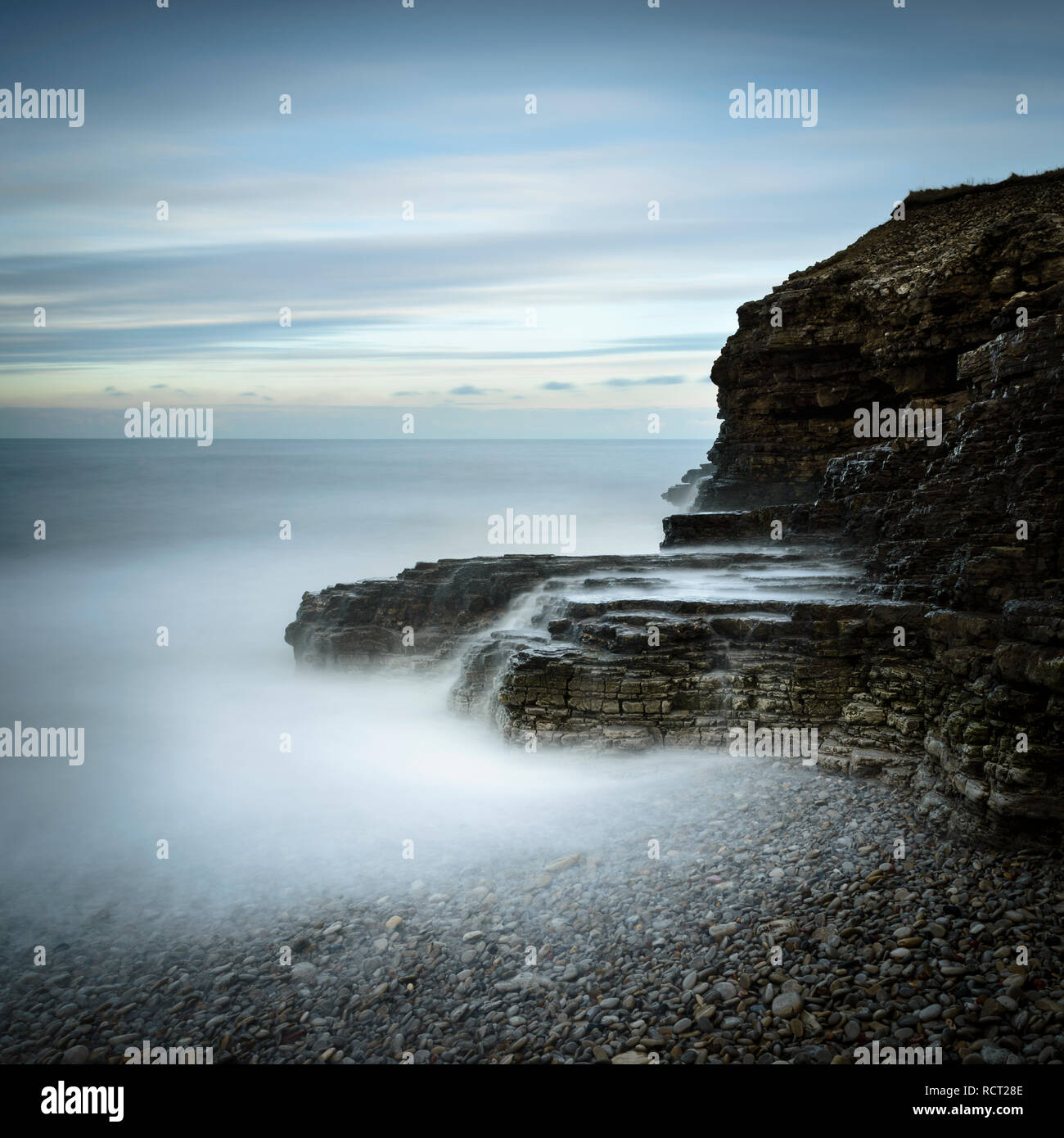 Wonderful ambient light created conditions for this long exposure of the cliffs, pebble beach and the streams of cascading water at Souter Lighthouse Stock Photo