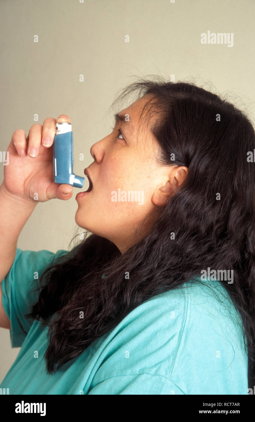 Chinese woman taking Ventolin salbutamol inhaler for asthma Stock Photo