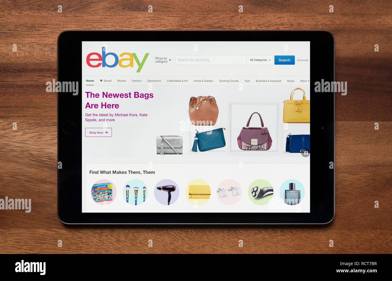 The website of Ebay is seen on an iPad tablet, which is resting on a wooden table (Editorial use only). Stock Photo