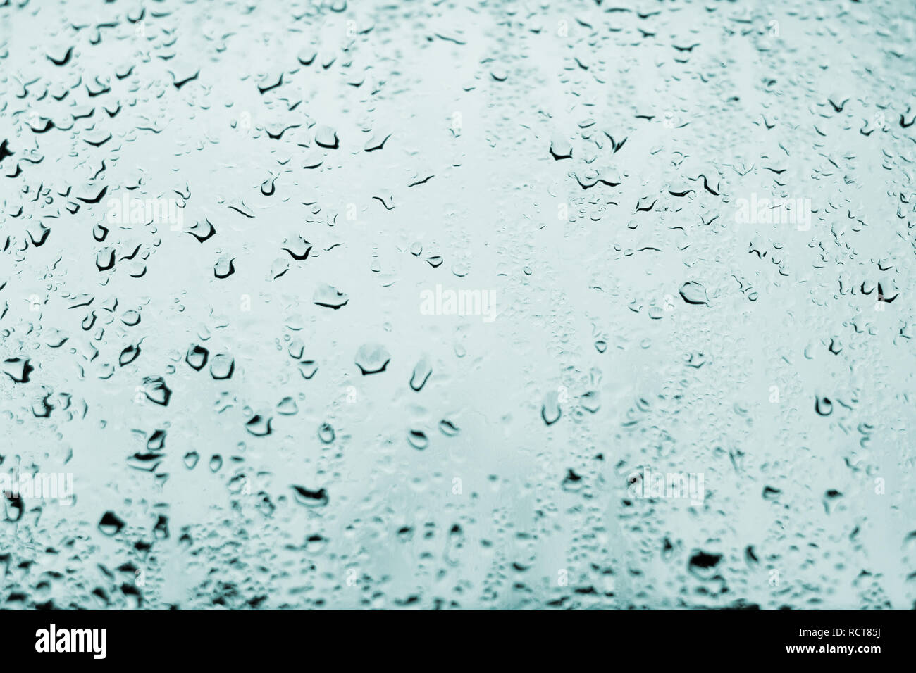 High contrast photo of drops of rain on a window glass with light pale cobalt blue color Stock Photo