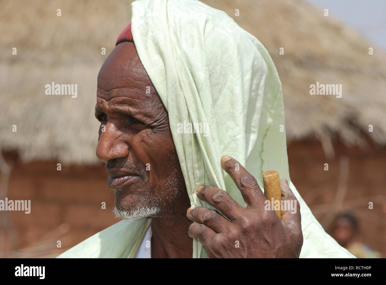 An old Fulani man in Niger, Africa, leans on his walking stick and looks into the distance Stock Photo