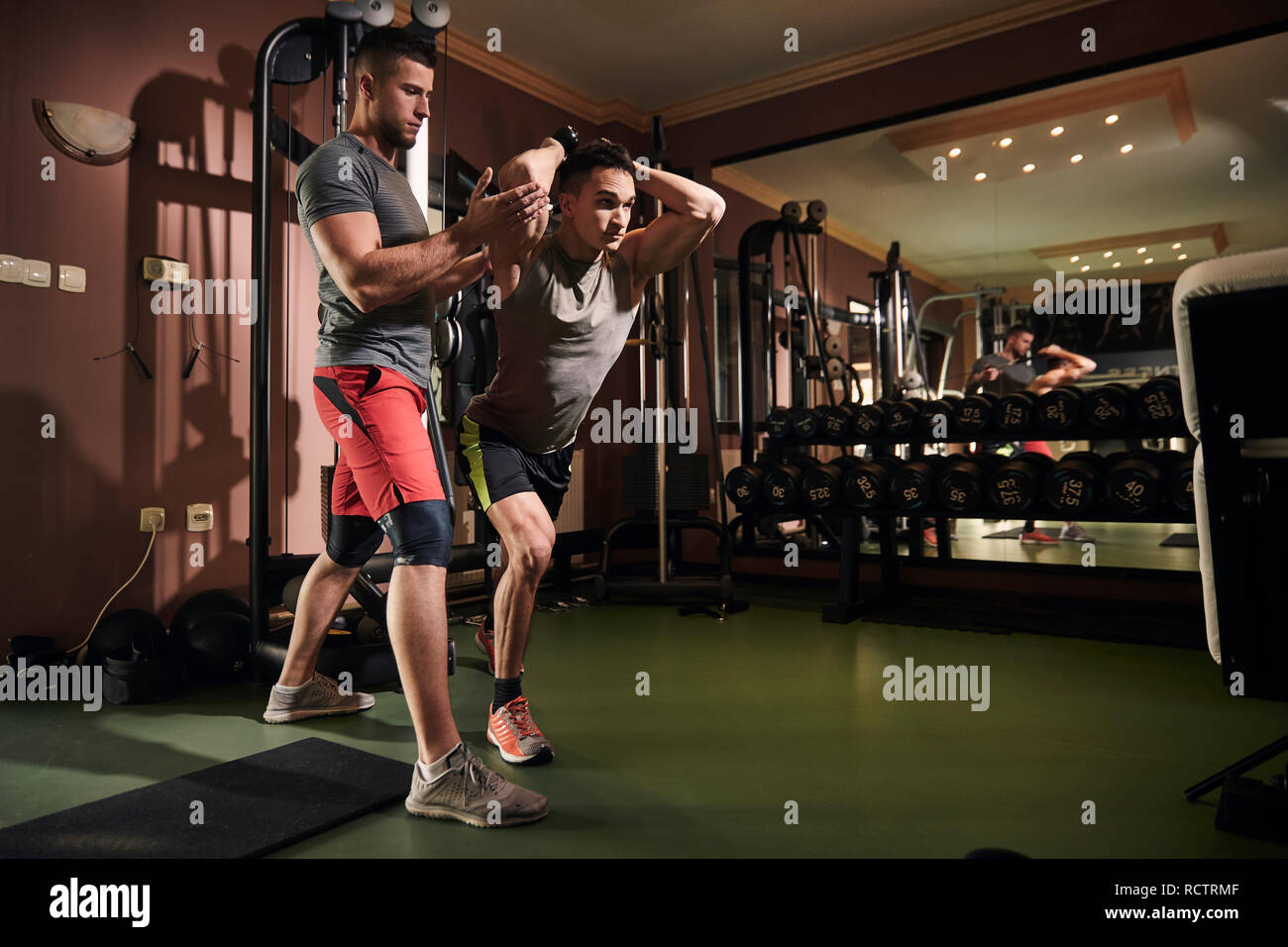 two young man coach helping other man while doing overhead cable extension exercise. In gym at home. Professional fitness equipment Stock Photo Alamy