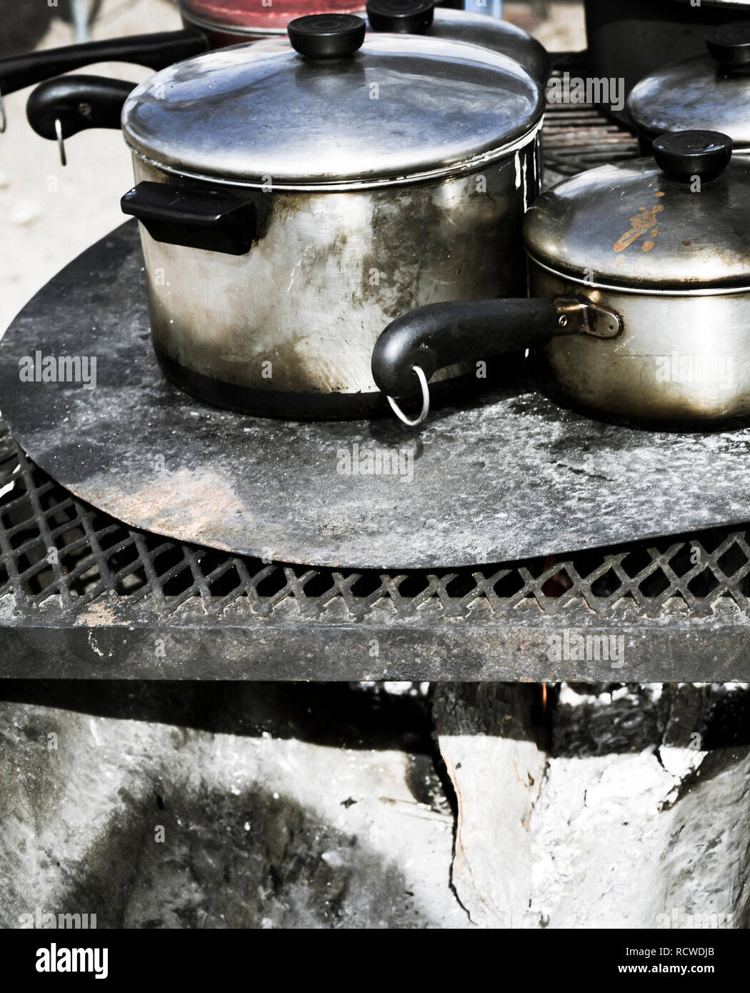 https://c8.alamy.com/comp/RCWDJB/close-up-of-aluminum-pots-and-pans-with-lids-cooking-outside-on-a-fire-pit-RCWDJB.jpg