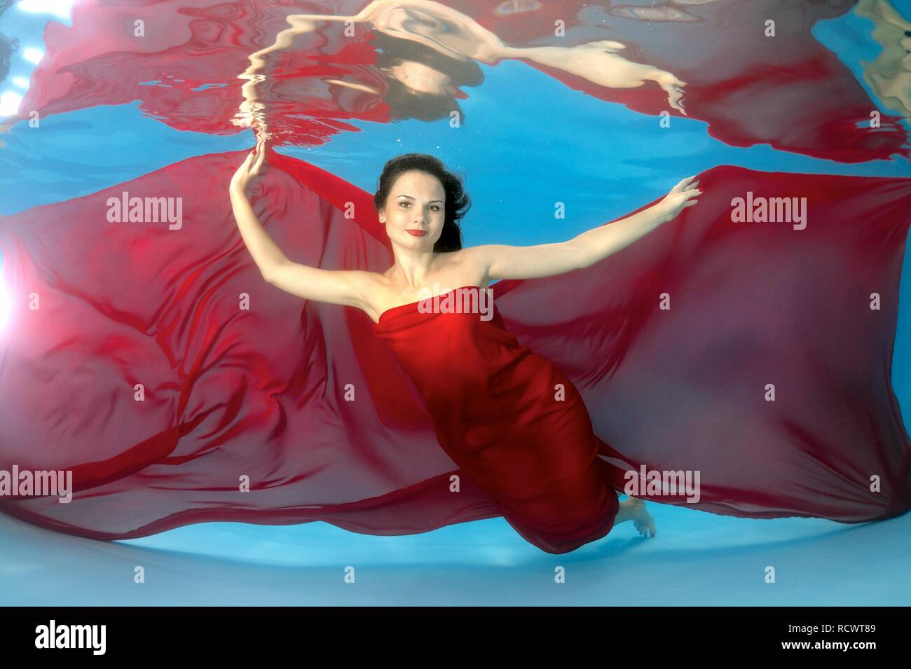 Woman presenting underwater fashion in pool Stock Photo
