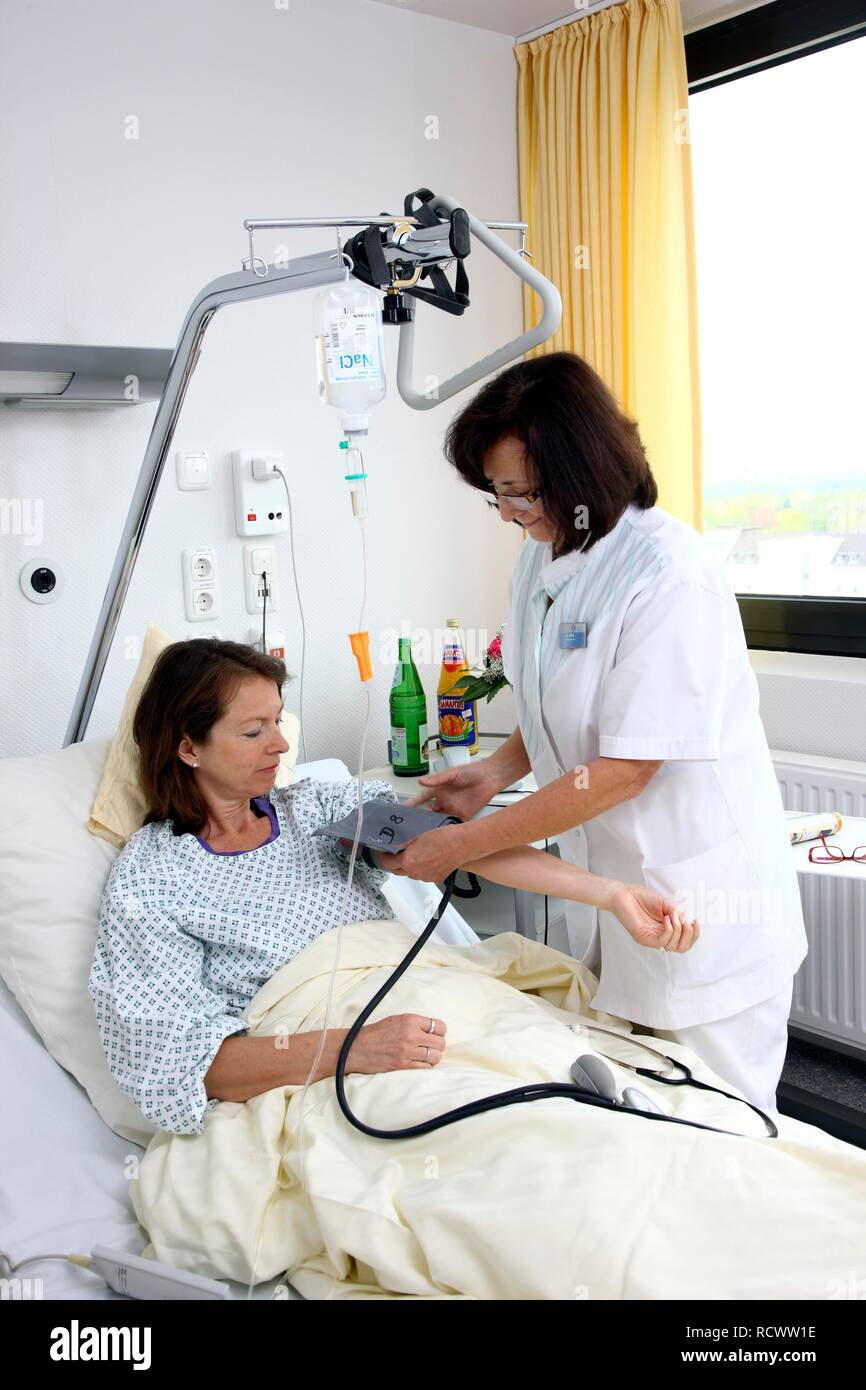 Nurse checking the blood pressure of a patient lying in a hospital bed