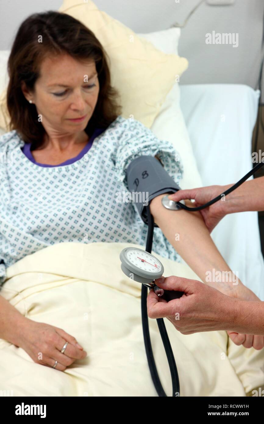 Nurse checking the blood pressure of a patient lying in a hospital bed