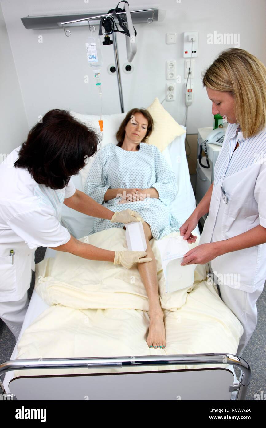 Nurses changing the dressing of a patient in a hospital bed Stock Photo