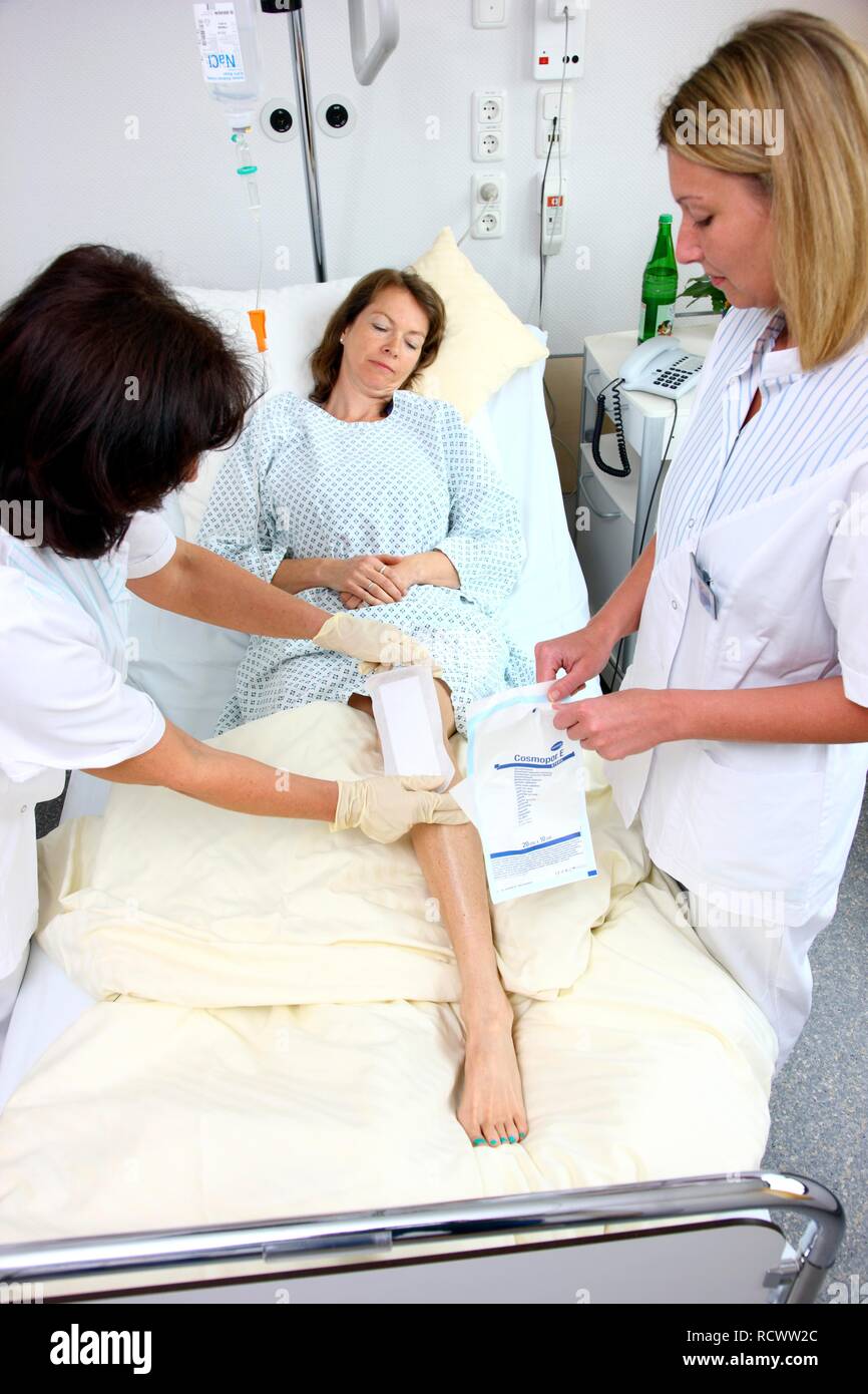 Nurses changing the dressing of a patient in a hospital bed Stock Photo