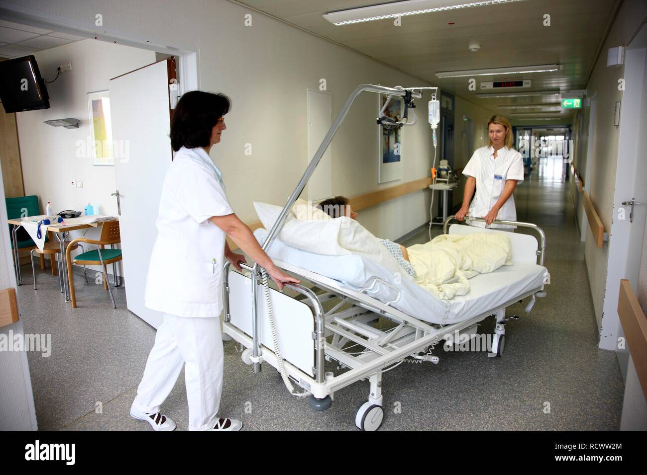 Nurses transporting a patient in a bed within the station of a hospital Stock Photo