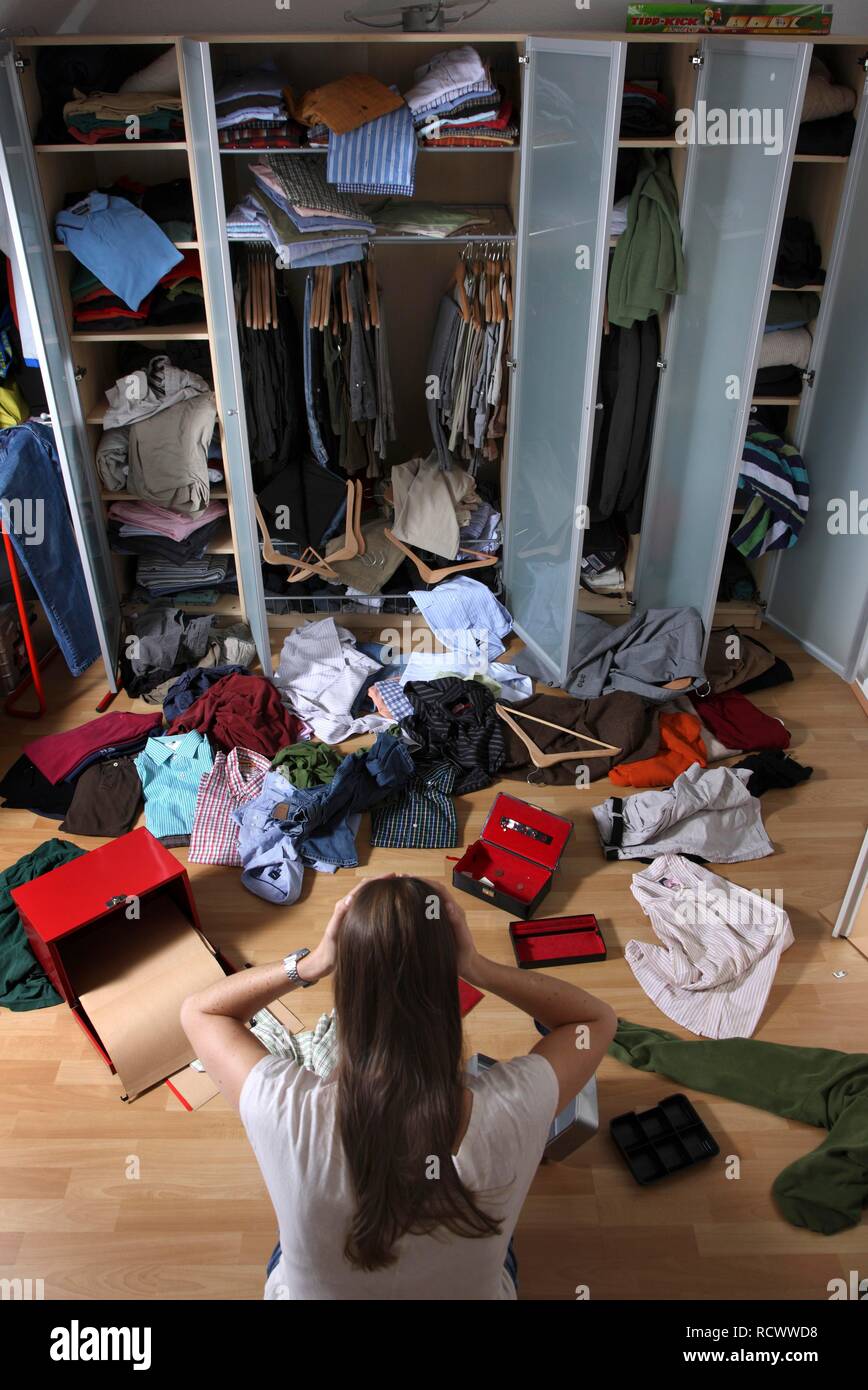 Young woman discovering the scene of a burglary, ransacked closet, jewellery box cleared out, cash box forced open Stock Photo