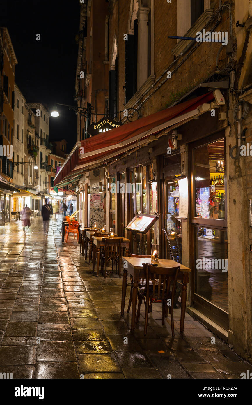 Venice, Italy - March 19, 2018: Outdoor cafe at narrow street in Venezia at night Stock Photo