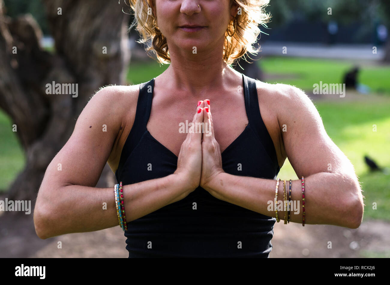 Beautiful young woman meditates in yoga asana Padmasana - Lotus pose on the wooden deck in the autumn park. Stock Photo