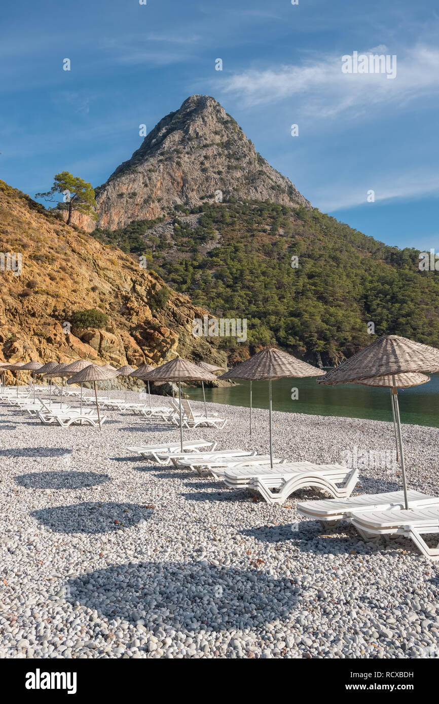Beach umbrellas and sunbeds on the Adrasan beach at Mediterranean coast in Turkey Stock Photo