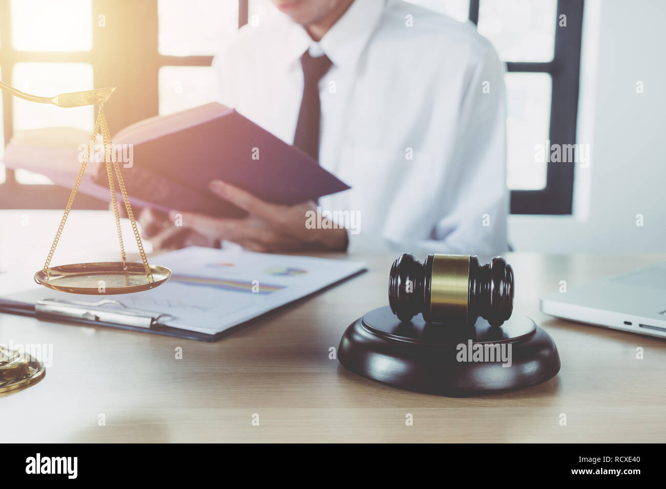 Male lawyer working with legal book on desk table with laptop,gavel,scale.justice and law
