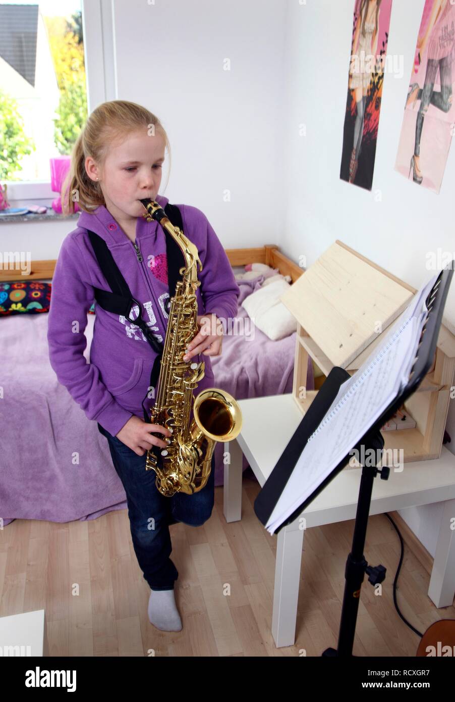 Girl, 10 years, practising saxophone in her room Stock Photo