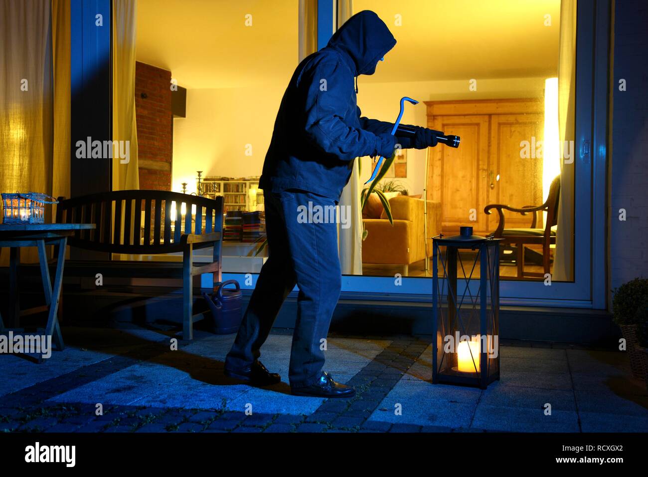 Burglar wants to forcefully enter a house, sneaks onto the terrace, symbolic image for domestic burglary Stock Photo