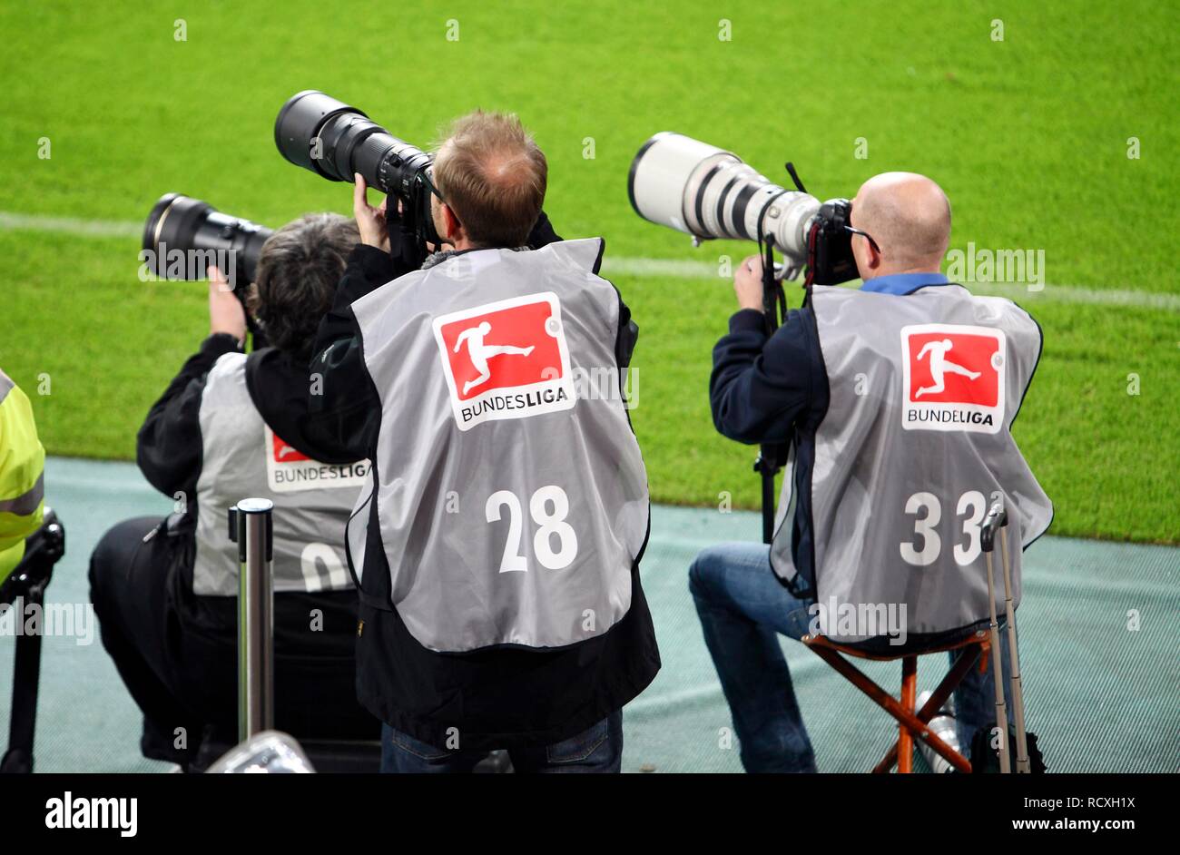 Sports photographers with telephoto lenses on the edge of a football