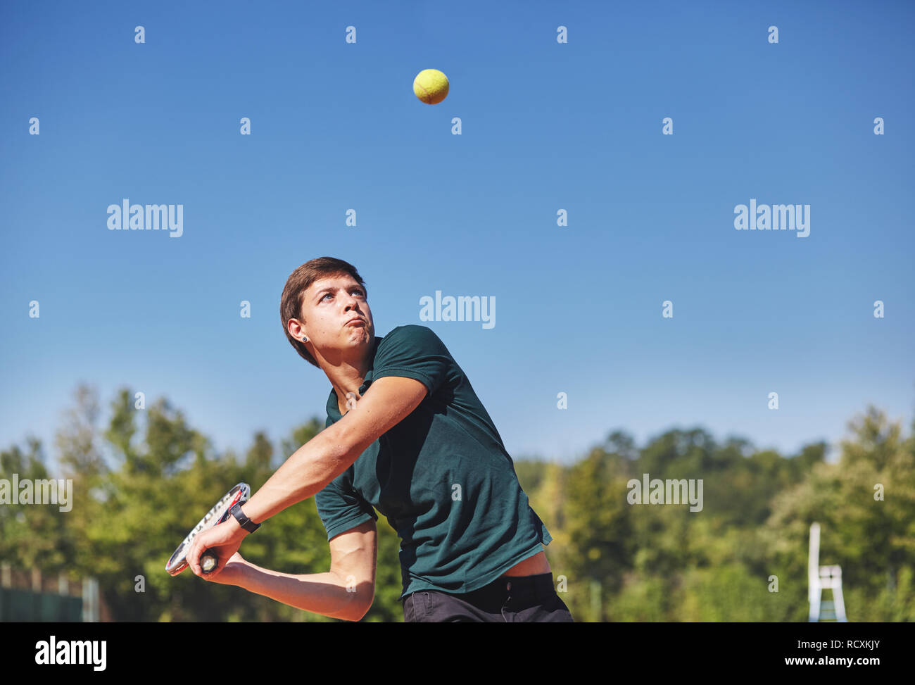a Man playing tennis on the court on a beautiful sunny day Stock Photo