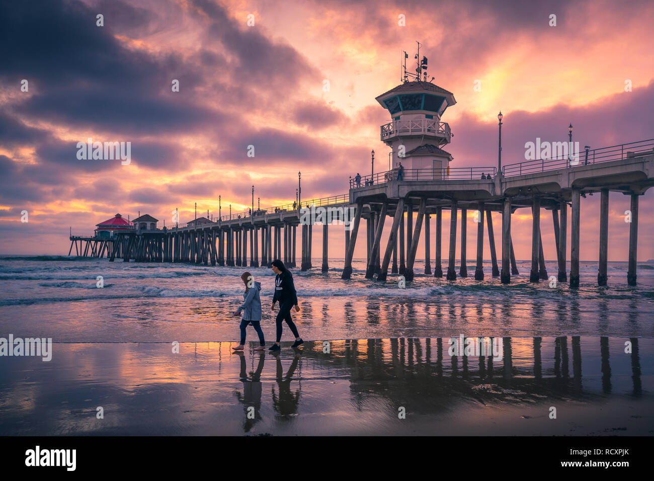 LOS ANGELES, CA/USA - JAN 11, 2019:  People walking along the beach at sunset near Huntington Beach Pier in Los Angeles, California Stock Photo