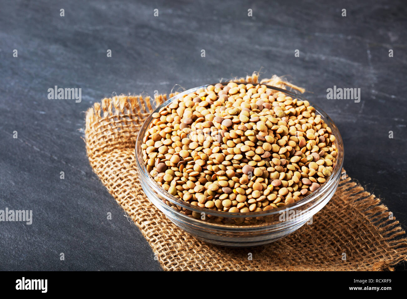 Raw lentils on balck stone background. Healthy vegetarian food concept