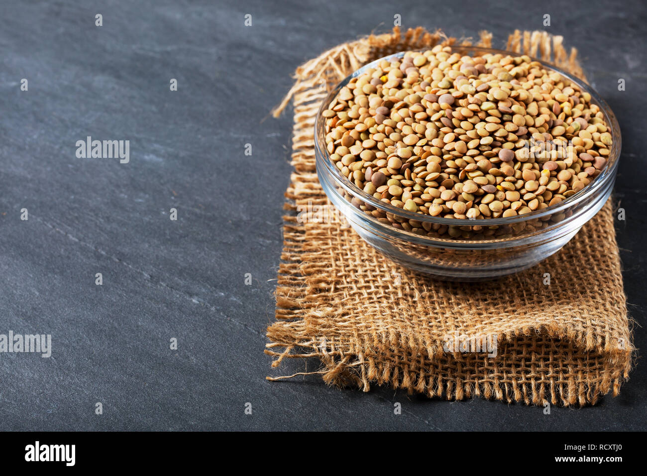 Raw lentils on balck stone background. Healthy vegetarian food concept