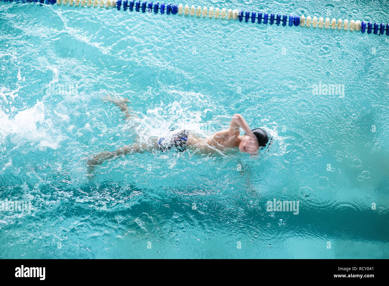 one healthy sport little boy swimming in blue water pool with effort