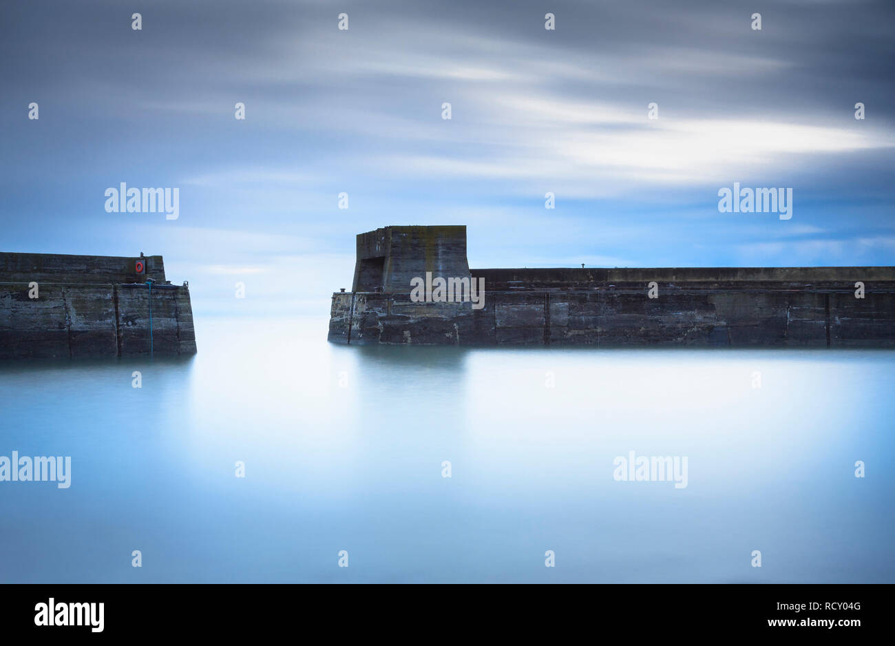 A early morning long exposure of the harbour walls and tower at Craster, just down from Dunstanburgh Castle on the Northumberland Coast. Stock Photo
