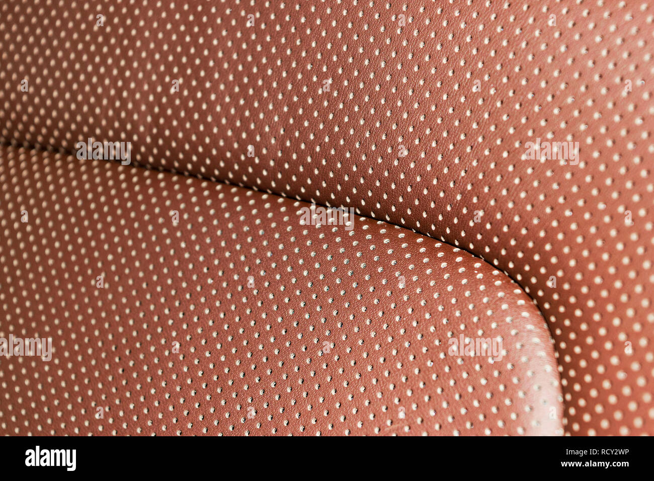 Modern luxury Car brown leather interior. Part of leather car seat details with white stitching. Interior of prestige car. Comfortable perforated leat Stock Photo