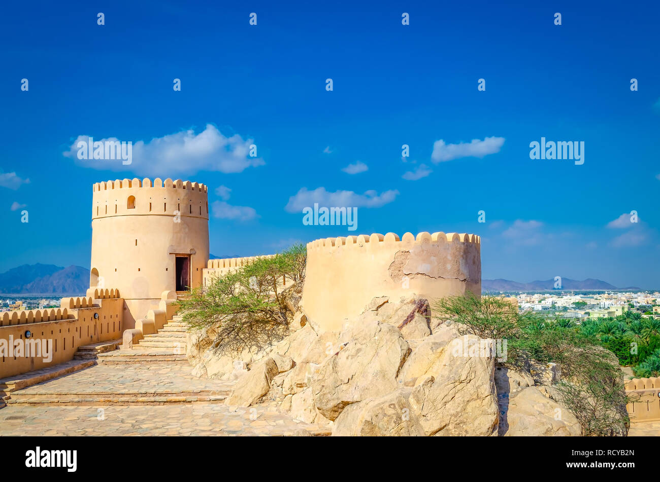 Turret of old, abandoned fort in Nakhal, Muscat, Oman on a clear and bright sunny day. Blue sky with minimal clouds and a desert oasis in the backgrou Stock Photo