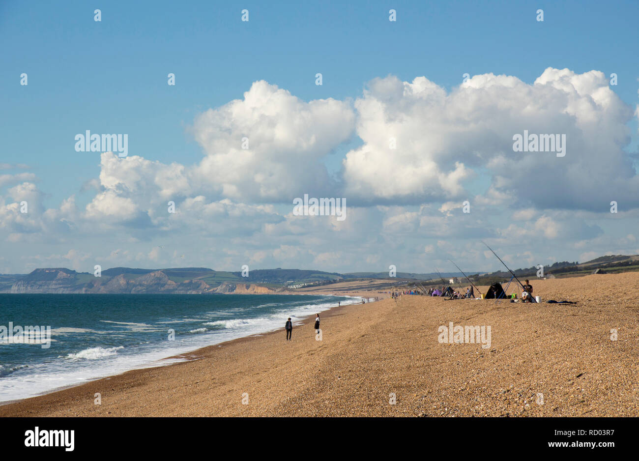 Anglers on a hot day sea fishing from the shore on the shingle of