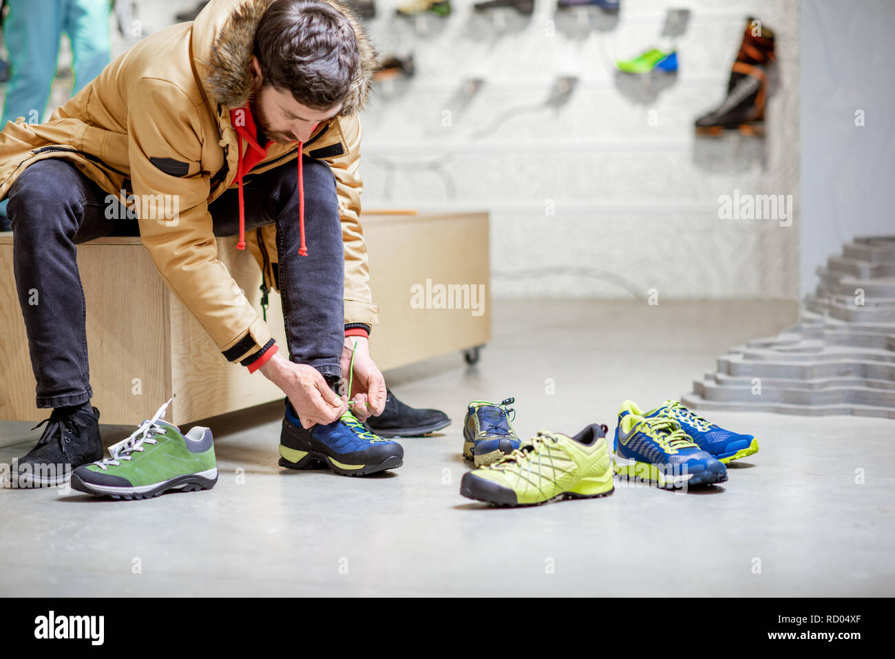 Man in winter jacket trying shoes for mountain hiking sitting in the