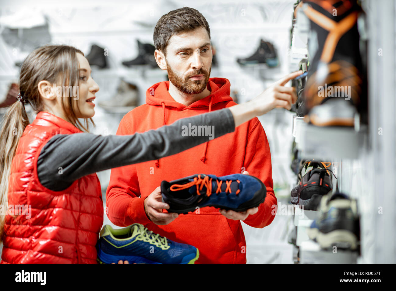 Mam and woman in red sports clothes choosing trail shoes for hiking