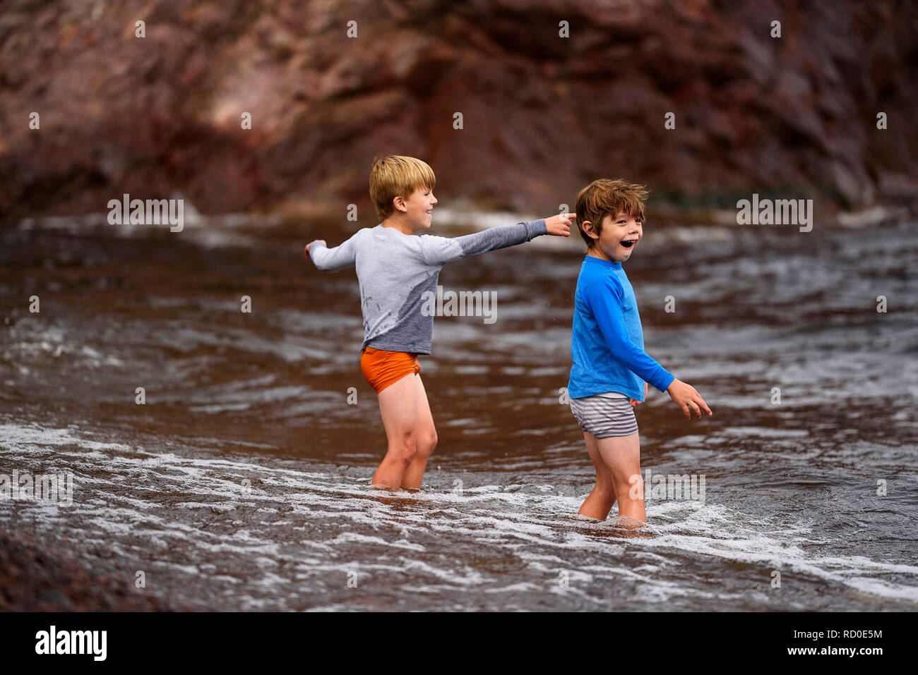 Two boys standing knee deep in the sea having fun, United States Stock Photo