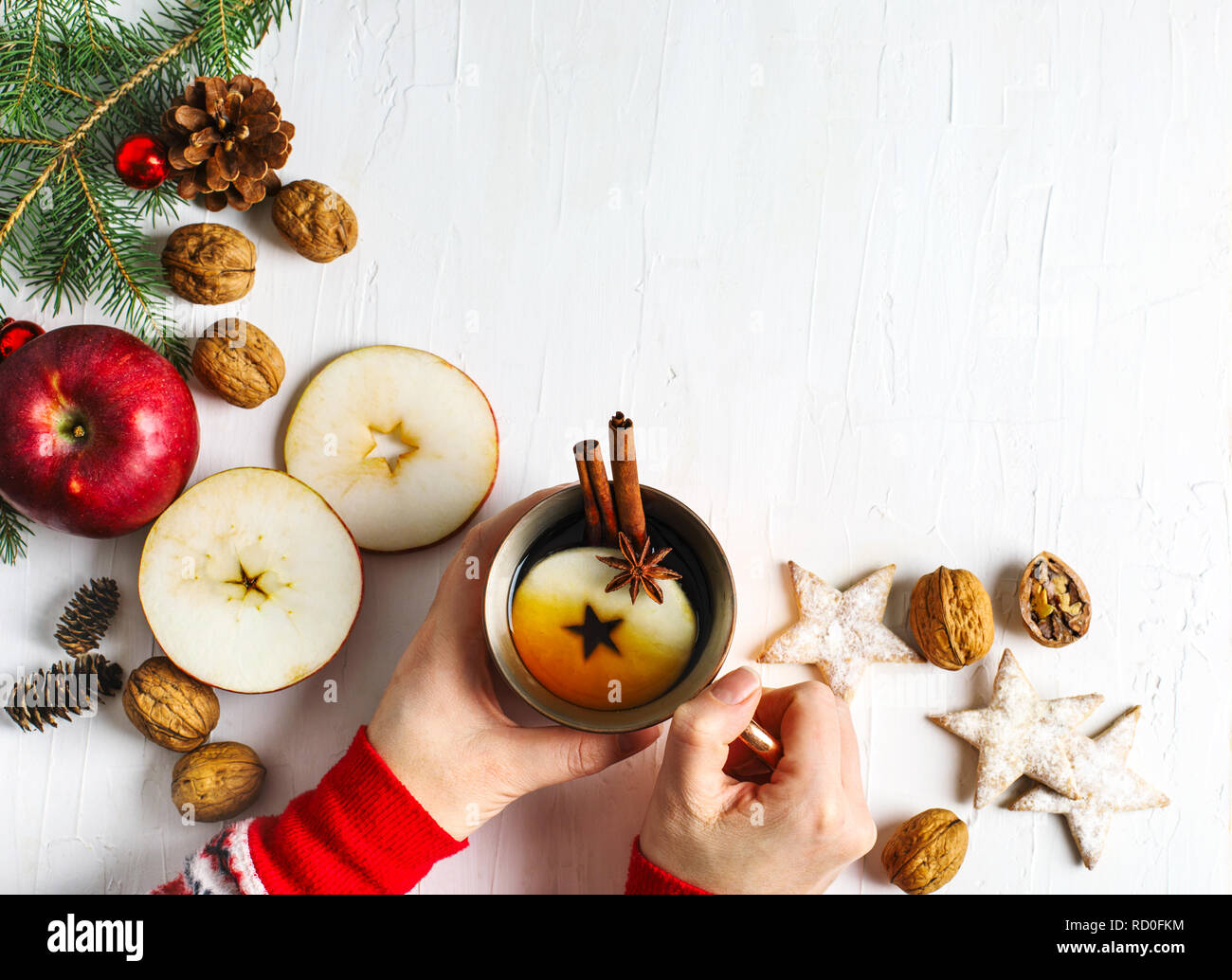 Woman's hand holding a cup of apple tea and Christmas decorations Stock Photo