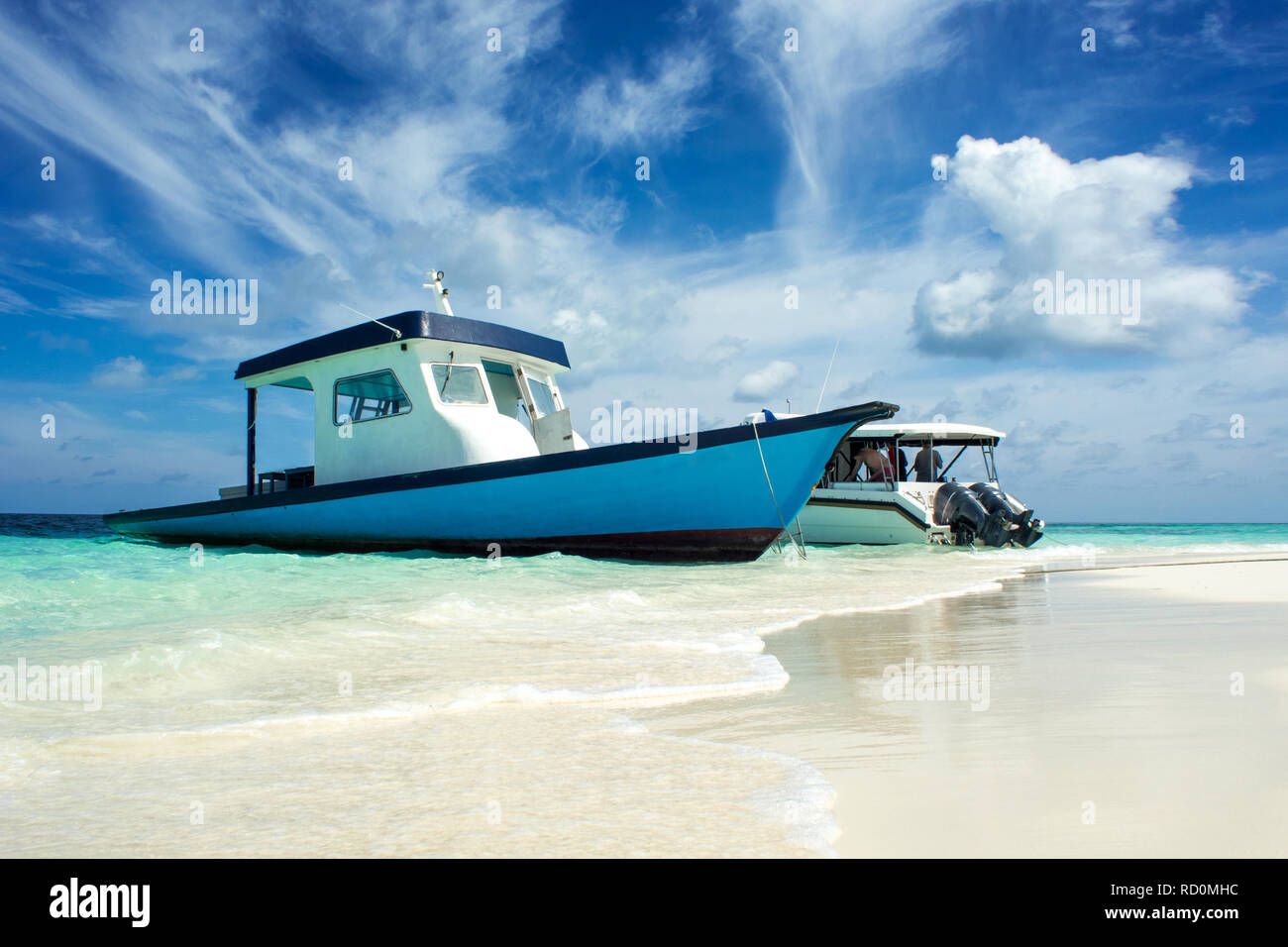 Small boats moored to the shore of an uninhabited island. Paradise tropical island, white sand and clear water. Landscape with turquoise surf. Stock Photo