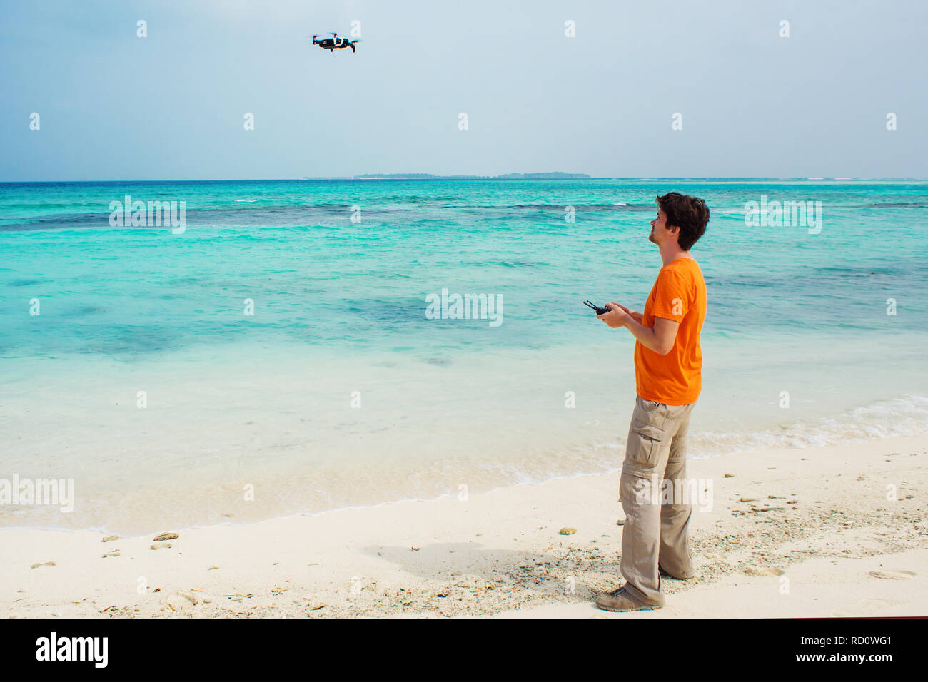 Guy launches a drone over the sea, photo and video shooting on quadrocopter. Drone flights over water, testing. Stock Photo