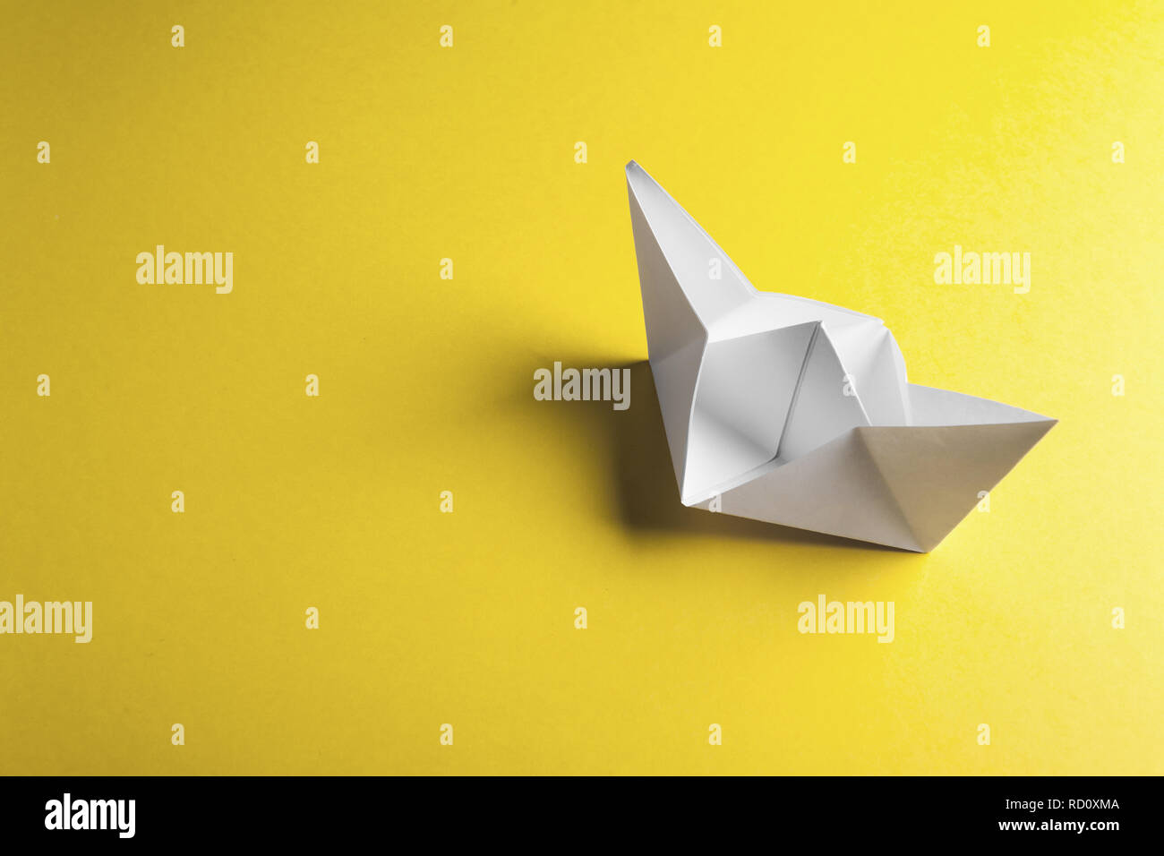 Paper boat on a yellow background with copyspace Stock Photo