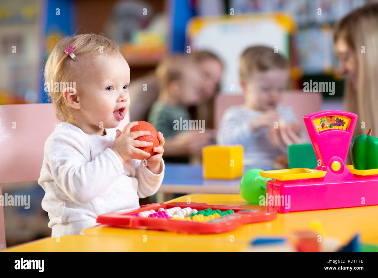 Adorable baby girl playing with educational toys with group of nursery ...