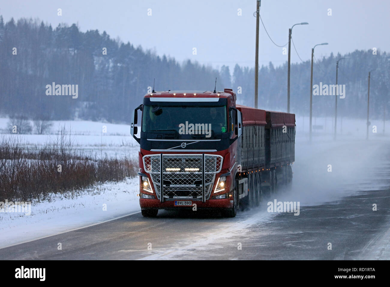 Salo, Finland - December 22, 2018: Red Volvo FH16 transporter driving on snowy highway in winter snowfall in South of Finland. Stock Photo
