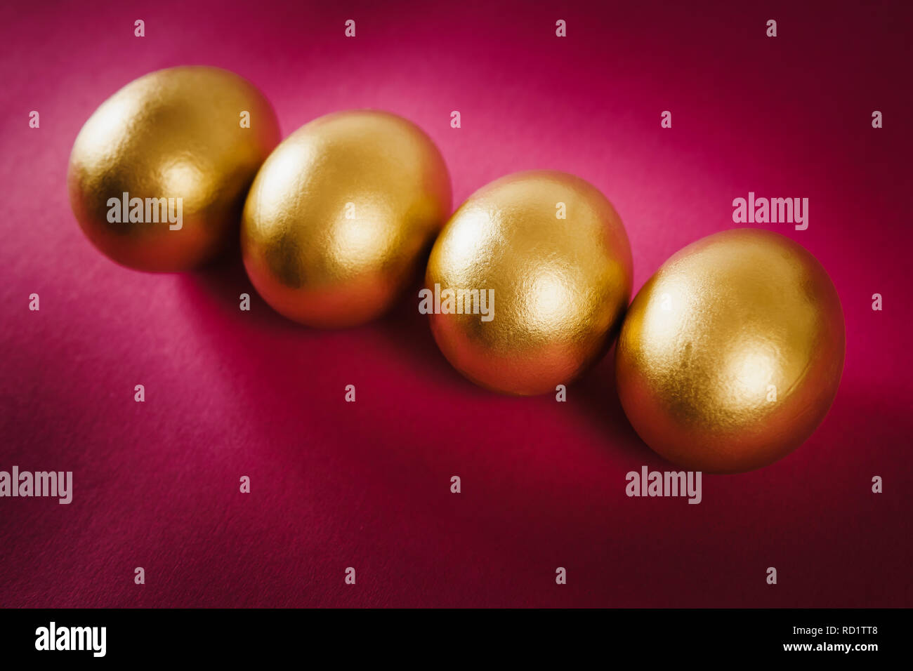 four gold Easter eggs on a purple background Stock Photo