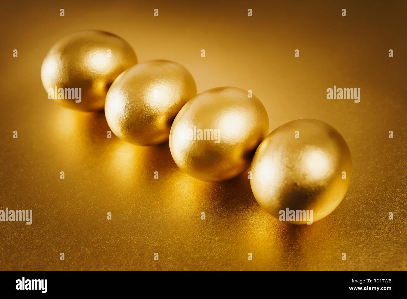 four gold Easter eggs on a shiny background Stock Photo