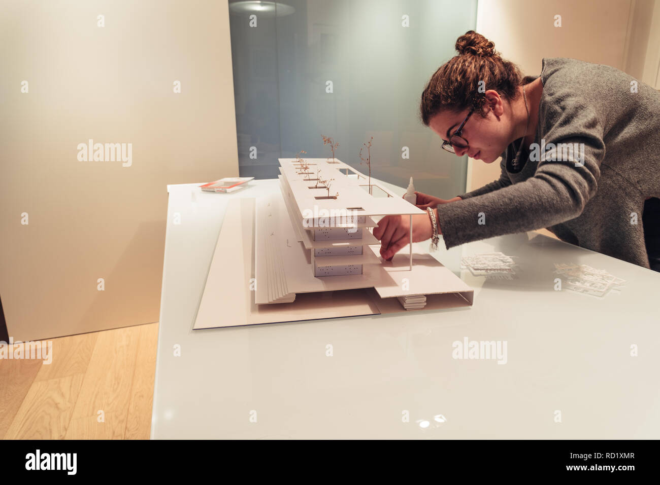 Female architect working on architecture model made with cardboard on table in office of architectural firm Stock Photo