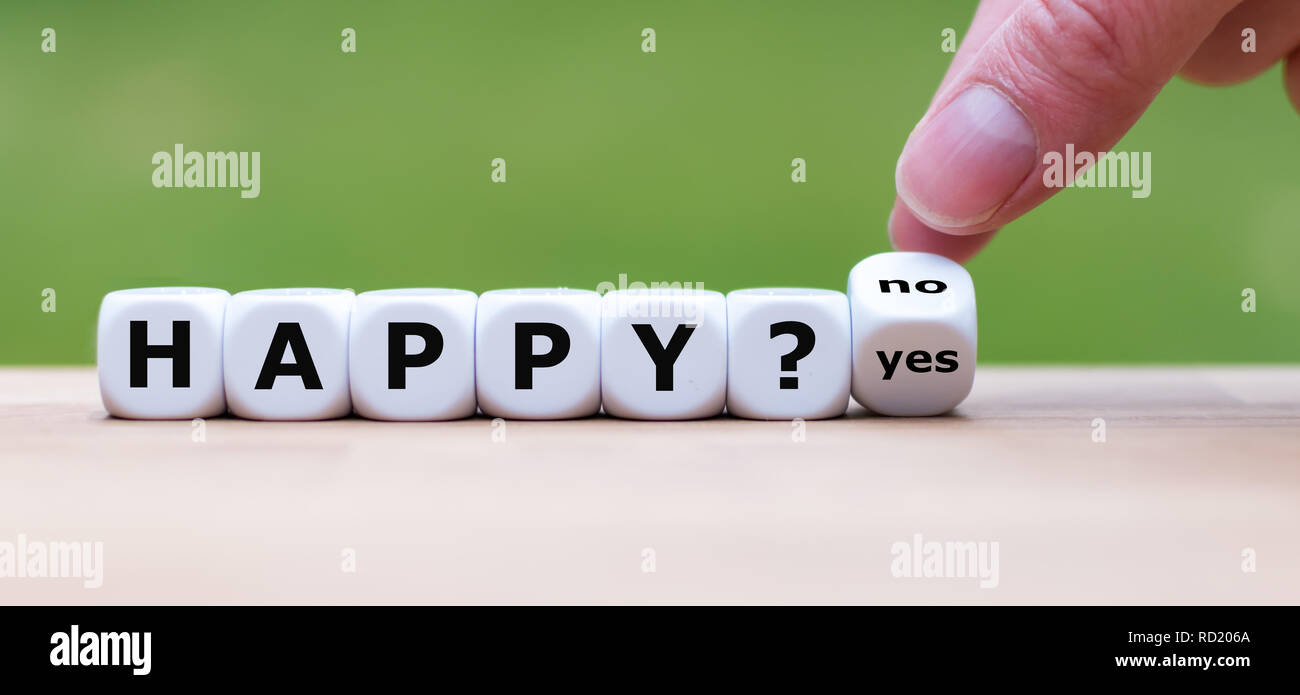 Being happy? Hand turns a dice and changes the word "no" to "yes" (or vice versa) Stock Photo