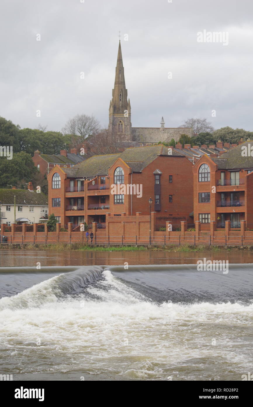 St Leonards Church beyond Trews Weir on the River Exe. Exeter, Devon