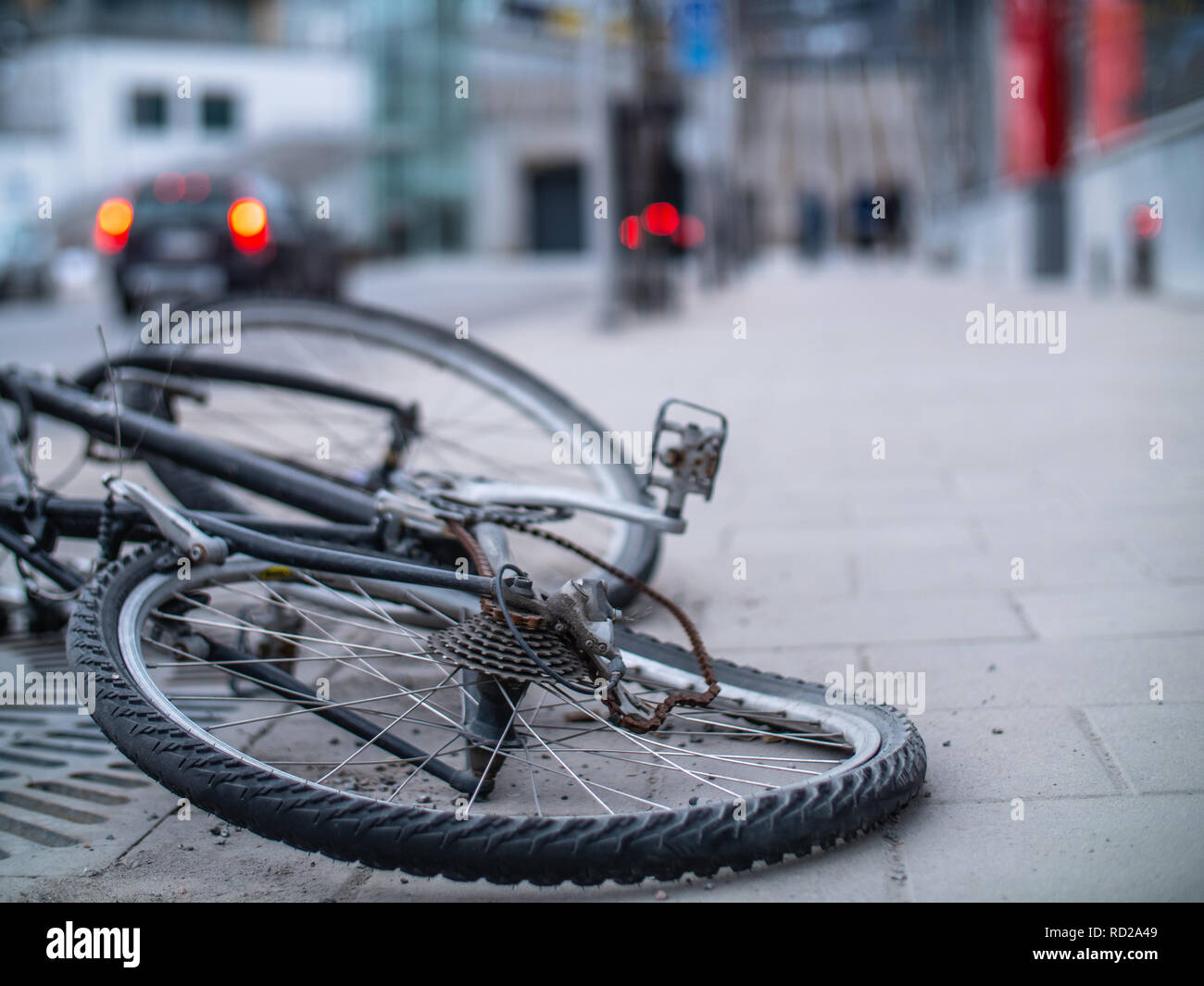 An old broken and bent bicycle with a rusted chain discarded in the street Stock Photo