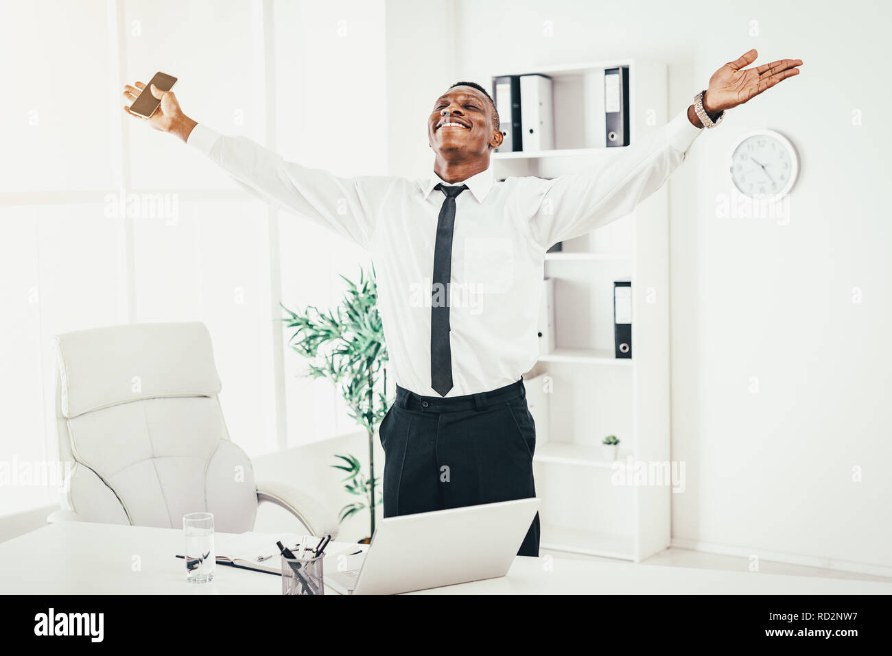 Successful African businessman celebrating success with raised arms in ...