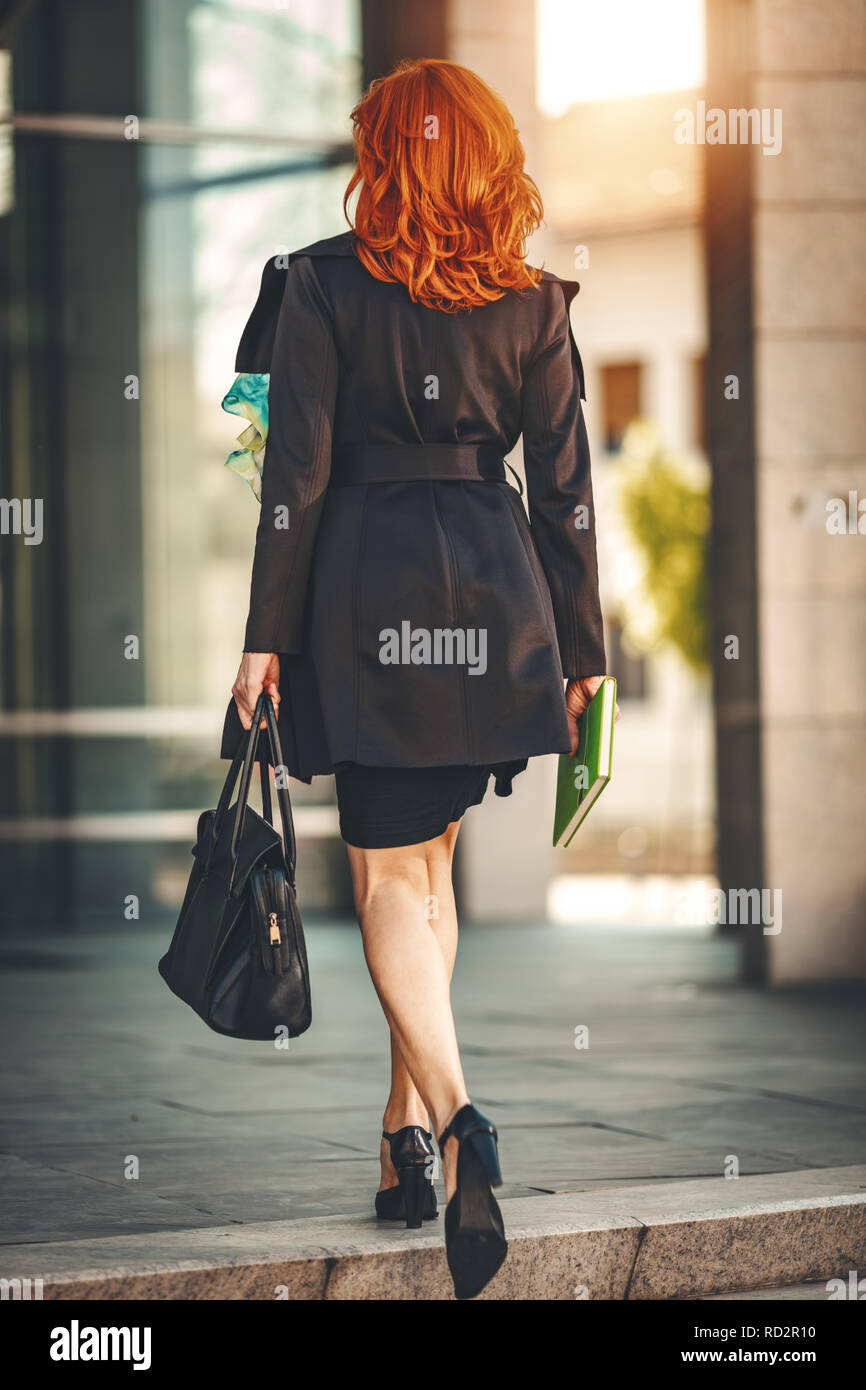 Rear view of a business woman is walking on the way in office building ...
